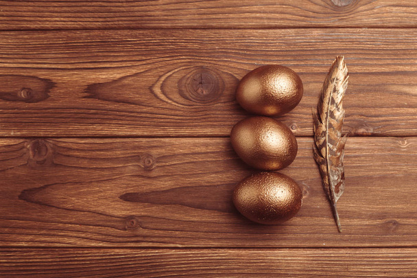 gold easter eggs on wooden table - Fotoğraf, Görsel