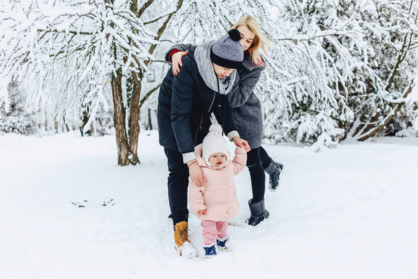 стильная счастливая молодая семья гуляет с ребенком на зимней улице, мама, папа, ребенок
 - Фото, изображение