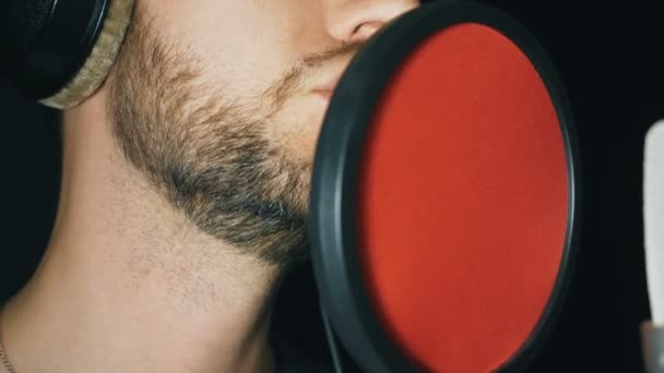 Bouche de chanteur masculin chantant en studio sonore. Un homme méconnaissable enregistrant une nouvelle chanson. Le type à la barbe chante au micro. Travail de musicien créatif. Fond sombre. Ralenti Fermer
 - Séquence, vidéo