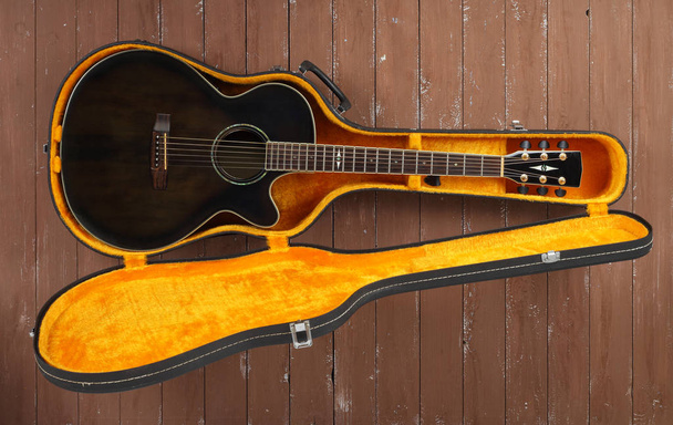 Instrument de musique - Guitare acoustique cutaway marron vue de dessus en étui rigide sur fond de bois
. - Photo, image
