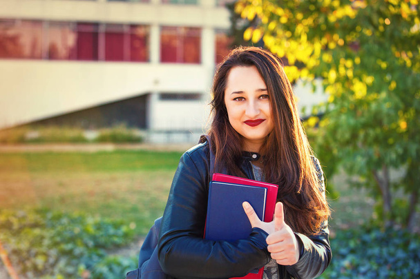 Молода жінка студентська прогулянка в кампусі коледжу показує великі пальці вгору жест
. - Фото, зображення