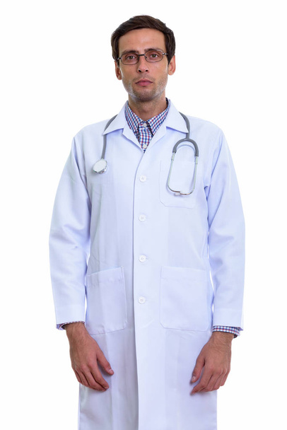 Studio shot of young handsome man doctor standing while wearing  - Φωτογραφία, εικόνα