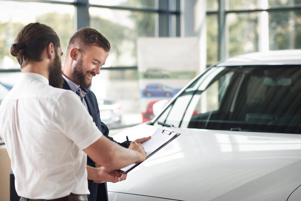 Customer of car signing documents of purchase on folder. - Фото, изображение