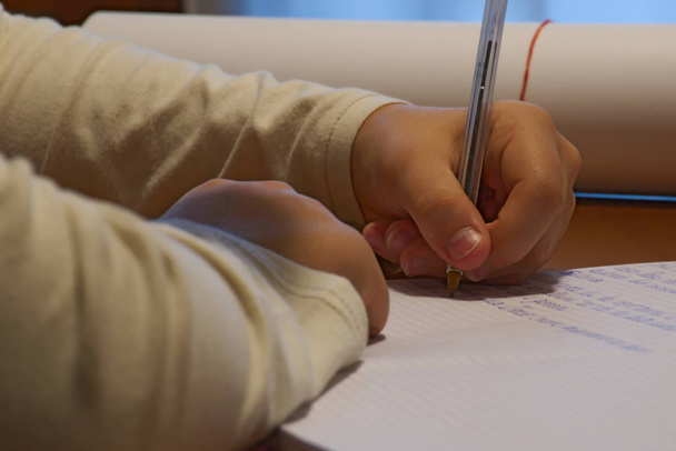 Hand eines linkshändigen Jungen, der Hausaufgaben schreibt - Foto, Bild