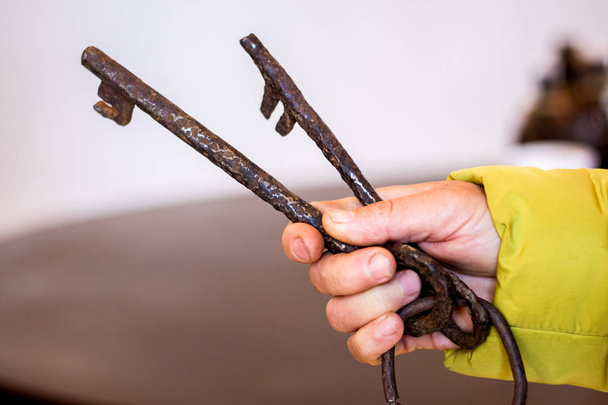 Yaşlı bir kadının elinde paslı anahtar taşı metal - Fotoğraf, Görsel