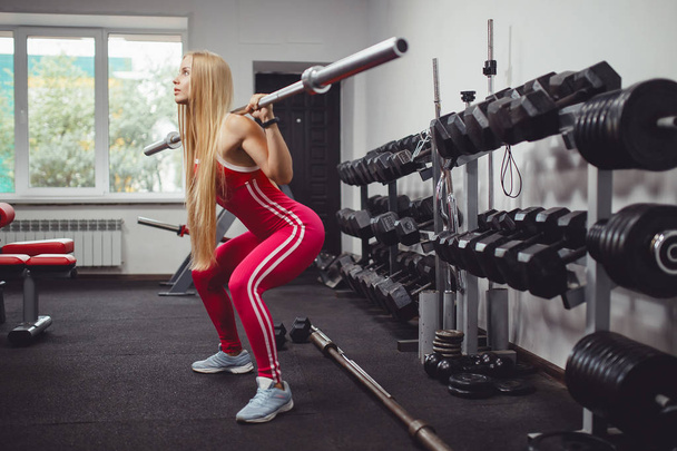 Fitness bar. A girl doing an exercise squat with barbell in gym. Concept fitness in gym. - Photo, Image
