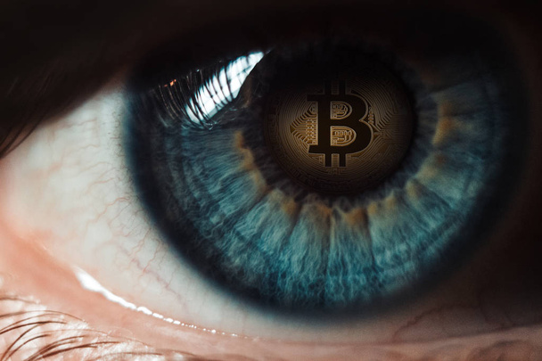 Auge einer Person mit dem Bitcoin-Logo in der Pupille - Foto, Bild