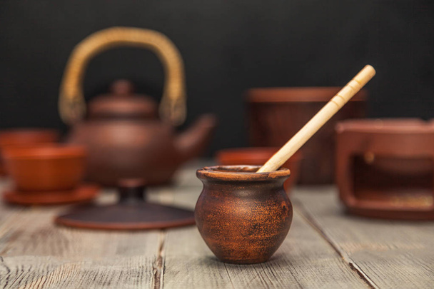 Cerimônia de chá, festa de chá. Pratos de argila. O mel flui de uma colher de madeira para um pote. Ainda vida
 - Foto, Imagem