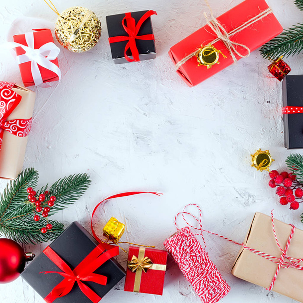 Weihnachten dekorativen Hintergrund mit Tannenzweigen, Zapfen, rote und schwarze Weihnachtsgeschenke, Kugel auf dem weißen Hintergrund. Kartenferienkonzept. Kopierraum, Ansicht von oben. - Foto, Bild