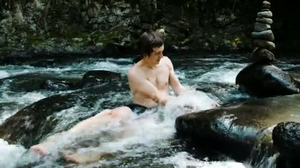 Man baadt in een rivier berg onder stenen en een cairn - Video
