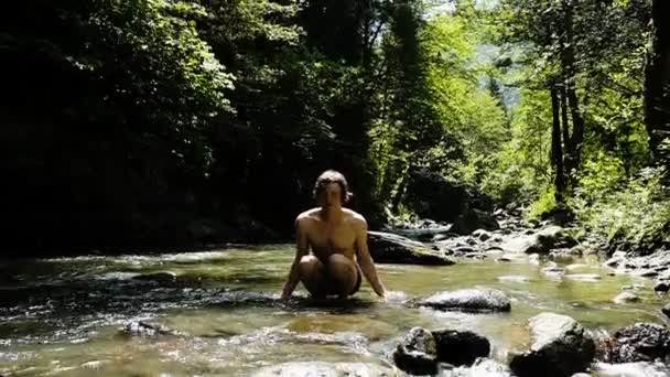 Mies nousee ylös ja roiskuu vuoristojokeen kesällä, kaveri seisoo vedessä ja iloitsee kuin lapsi, hidastettuna.
 - Materiaali, video