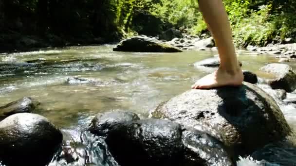 Γυναίκα σε ένα κοστούμι λουσίματος κάθεται σε μια πέτρα και το νερό εκτοξεύεται στο κρύο ποτάμι βουνό - Πλάνα, βίντεο