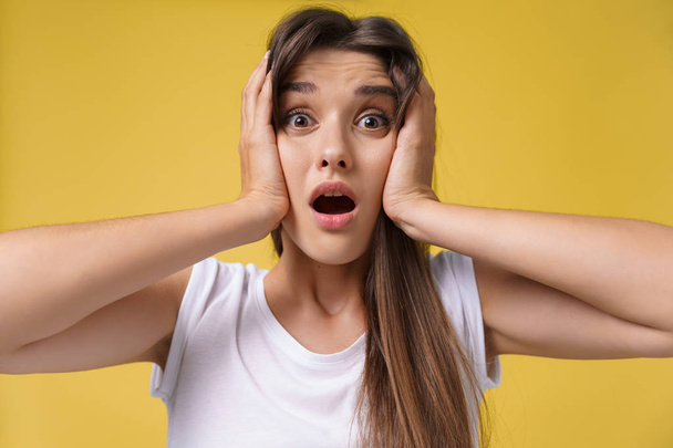 Portrait of shocked scared young woman in casual white shirt hearing bad news with disgusting emotion on her face, feeling scare, screaming. Human face expressions, body language - Photo, Image