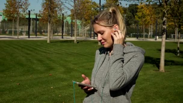 Woman runner listening to music on headphones using a smartphone. - Filmagem, Vídeo