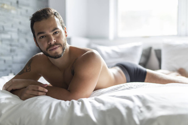 A young mexican man shirtless in white bed - Foto, immagini