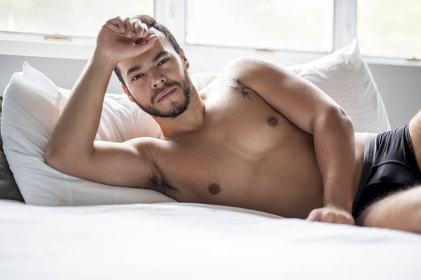 A young mexican man shirtless in white bed - Photo, Image