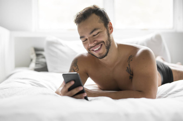 A young mexican man shirtless in white bed - Foto, Bild