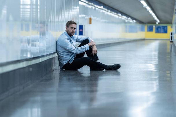 Young jobless business man suffering depression sitting on ground street underground leaning on wall alone looking desperate in Emotional pain Mental health Unemployment and Human emotions concept. - Photo, image