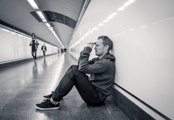 Miserable jobless young man crying Drug addict Homeless in depression stress sitting on ground street subway tunnel looking desperate leaning on wall alone in Mental disorder Emotional pain Sadness. - Fotoğraf, Görsel