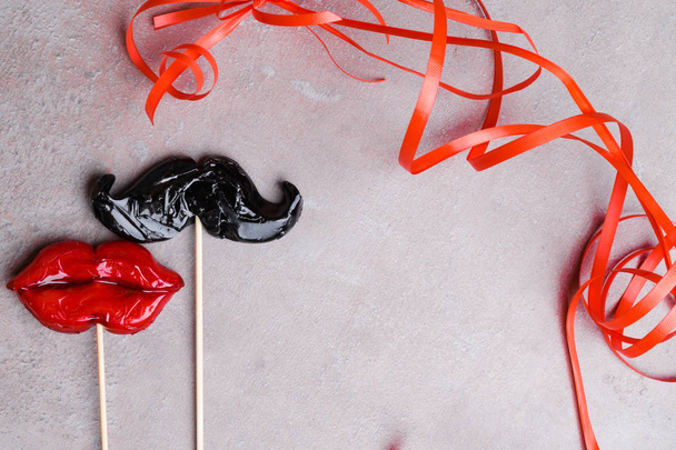 Akcesoria karnawałowe firm candy kobieta czerwone usta i człowiek wąsy na szarym tle kamień, pojęcie miłości, człowiek i kobiet, 14 lutego, pielenie, heteroseksualnych - Zdjęcie, obraz