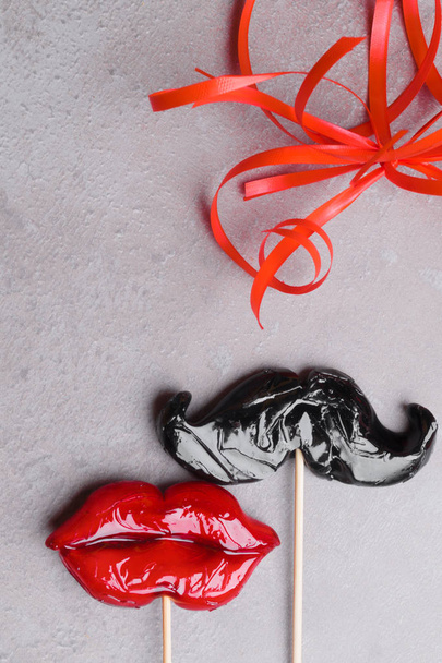 accessoires de fête carnaval bonbons femmes lèvres rouges et moustache homme sur un fond de pierre grise, concept d'amour, homme et femmes, 14 février, désherbage, hétérosexuel
 - Photo, image