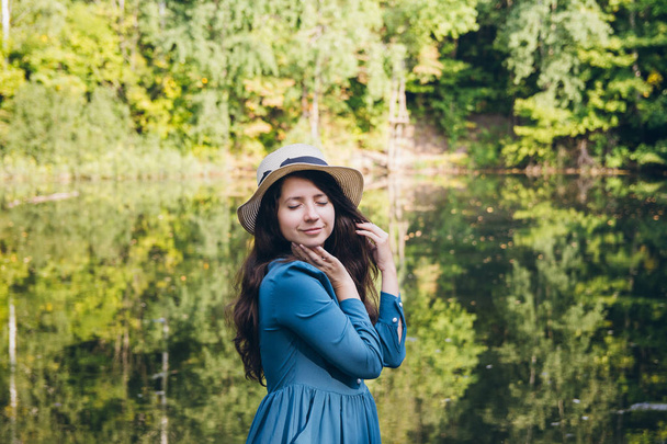 Beautiful young girl in a hat resting on the autumn lake on the bridge. Toning. - Foto, Bild