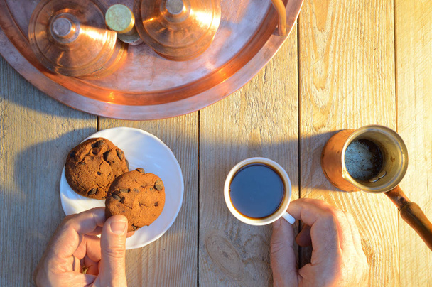 Hände nehmen Kaffee und Kekse aus einem rustikalen Holztisch - Foto, Bild