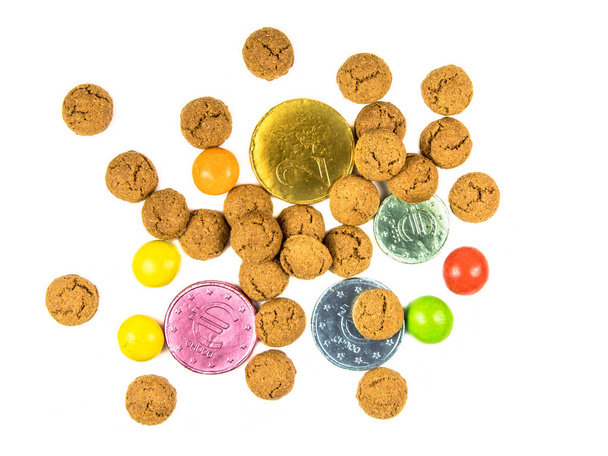 Bunch of scattered pepernoten cookies, chocolate money and sweets from above on white background for annual Sinterklaas holiday event in the Netherlands on december 5th - Photo, Image