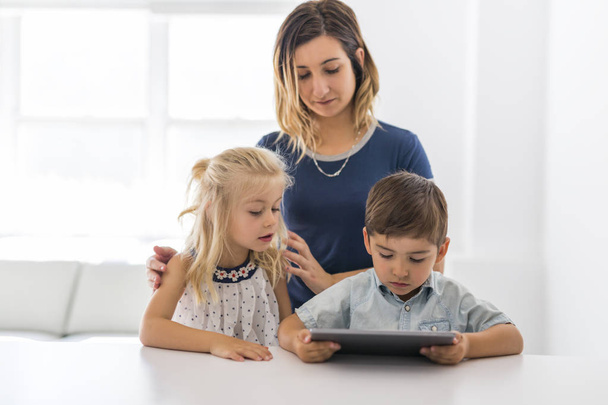 Adorable brother and sister young child using tablet with mother - Foto, afbeelding