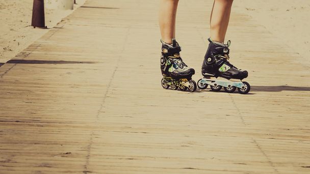 Woman slim legs wearing roller skates standing outside. Sport activity objects concept. - Foto, Imagem