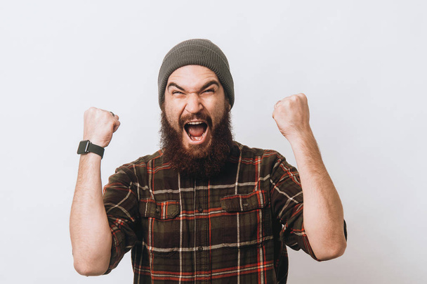 Amazed young bearded hipster man screaming over white background - Photo, Image