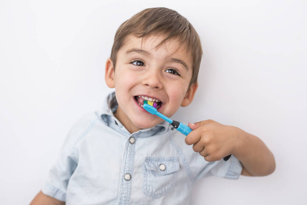 smiley boy cleans a teeth isolated on grey background - Фото, зображення