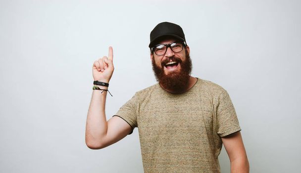 Happy smiling bearded man pointing up at copyspace over white background - Photo, image