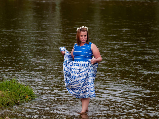 Portrait d'une jeune femme joyeuse dans une rivière vêtue d'une robe de soirée bleue
 - Photo, image