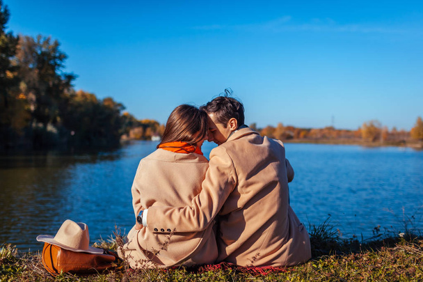 Young couple in love chilling by autumn lake. Happy man and woman enjoying nature and hugging. Romantic date - Photo, Image