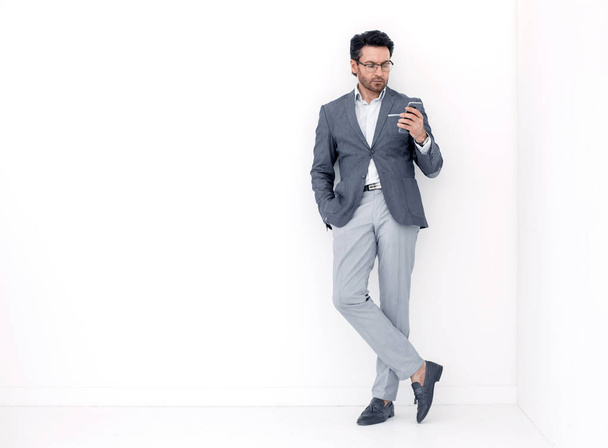 full height .business man looking at the screen of his smartphone - Фото, изображение
