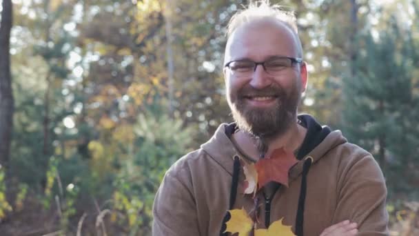 Portret van een bebaarde man met bril en een draadantenne op zijn kin, waarin de bladeren zijn geweven - Video