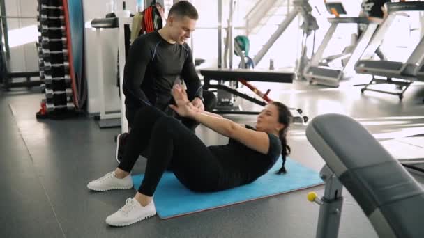 Εκπαίδευση μια γυναίκα αθλητισμός αρχάριος στο γυμναστήριο, ενώ η ίδια άντληση κοιλιά εκπαιδευτών προσωπικής εκγύμνασης - Πλάνα, βίντεο