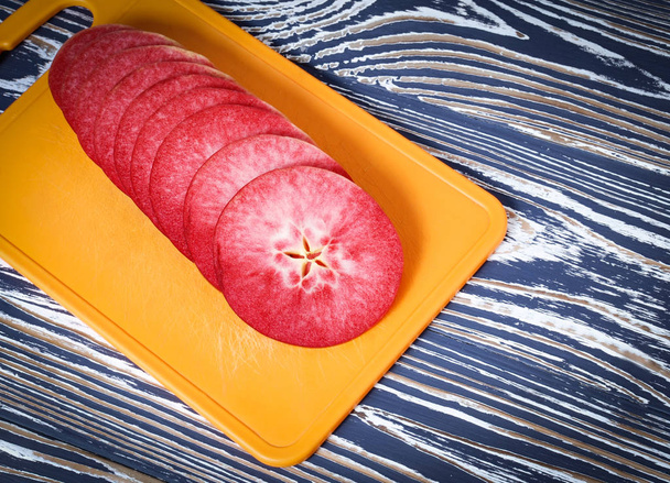 slices of red apple are on the yellow cutting board - Photo, Image