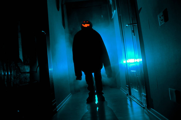 Halloween koncepció. A sötét folyosón sütőtök fej hátborzongató sziluettje. A köd a háttérben fény tónusú. - Fotó, kép
