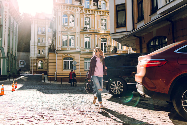 Sokak moda kavramı - dışarıda güzel bir kız, mavi jeans, güneş gözlüğü, sert ışık, kırmızı ceket, sonbahar hava portresi - Fotoğraf, Görsel