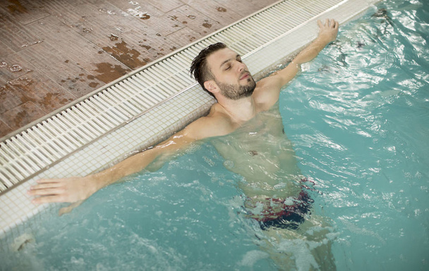 Handsome young man relaxing in hot tub in spa - 写真・画像