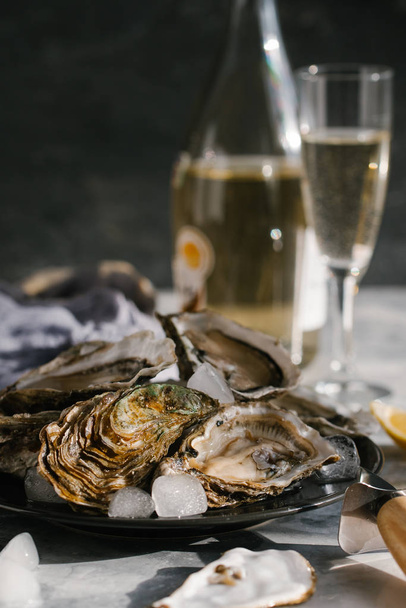 close up view of fresh oysters with ice and champagne on textured tabletop - Foto, Imagem