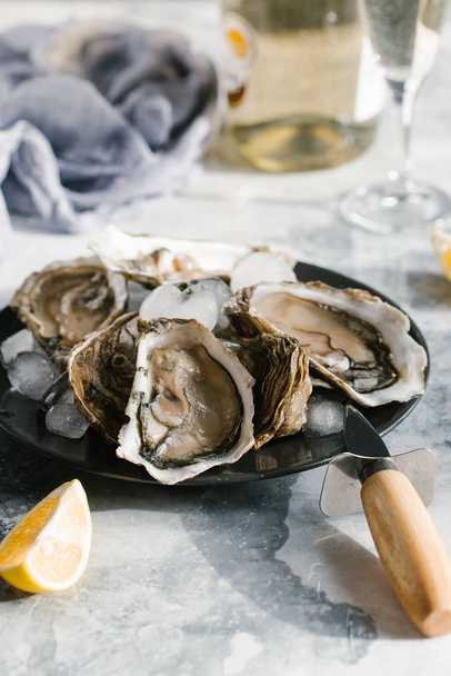 selectieve aandacht van verse oesters, citroen stukken en champagne op getextureerde tafelblad - Foto, afbeelding