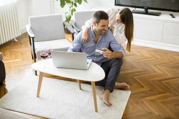 Χαρούμενο ζευγάρι ψάχνει στο διαδίκτυο και online αγορές στο σαλόνι στο σπίτι - Φωτογραφία, εικόνα