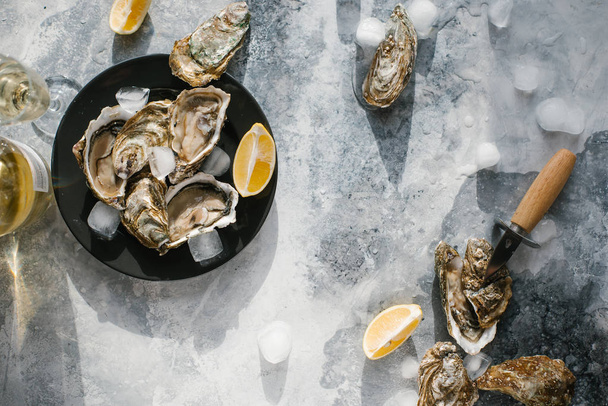 vista superior de ostras frescas, cubitos de hielo, champagne y trozos de limón en la mesa texturizada
 - Foto, Imagen