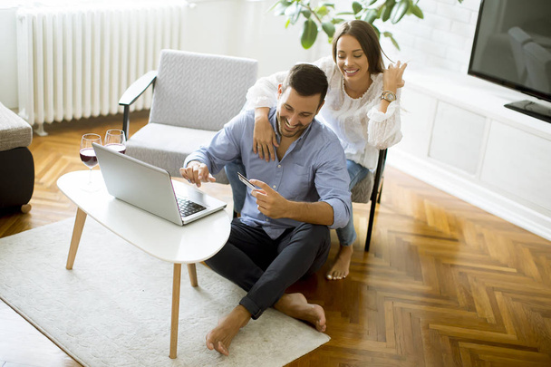 Casal alegre procurando internet e compras on-line na sala de estar em casa
 - Foto, Imagem