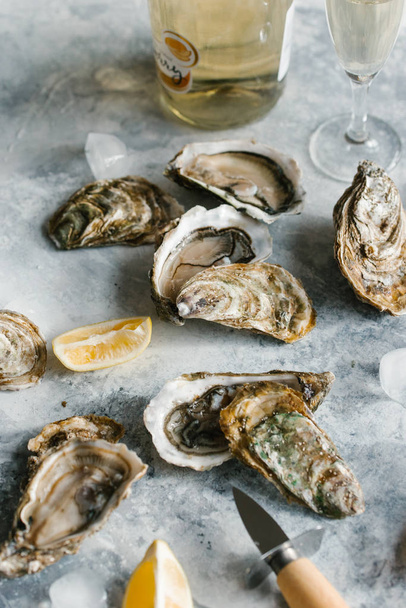 close up view of fresh oysters, lemon pieces and champagne on textured tabletop - 写真・画像