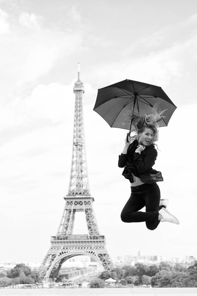 Happy woman travel in paris, france. Woman jump with fashion umbrella. Girl with beauty look at eiffel tower. Parisian isolated on white background. Travelling and wanderlust. Enjoy summer vacation - Photo, image