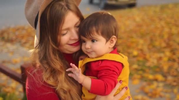 Casual Kaukasische moeder en haar multi race baby plezier buiten in herfst stad. - Video
